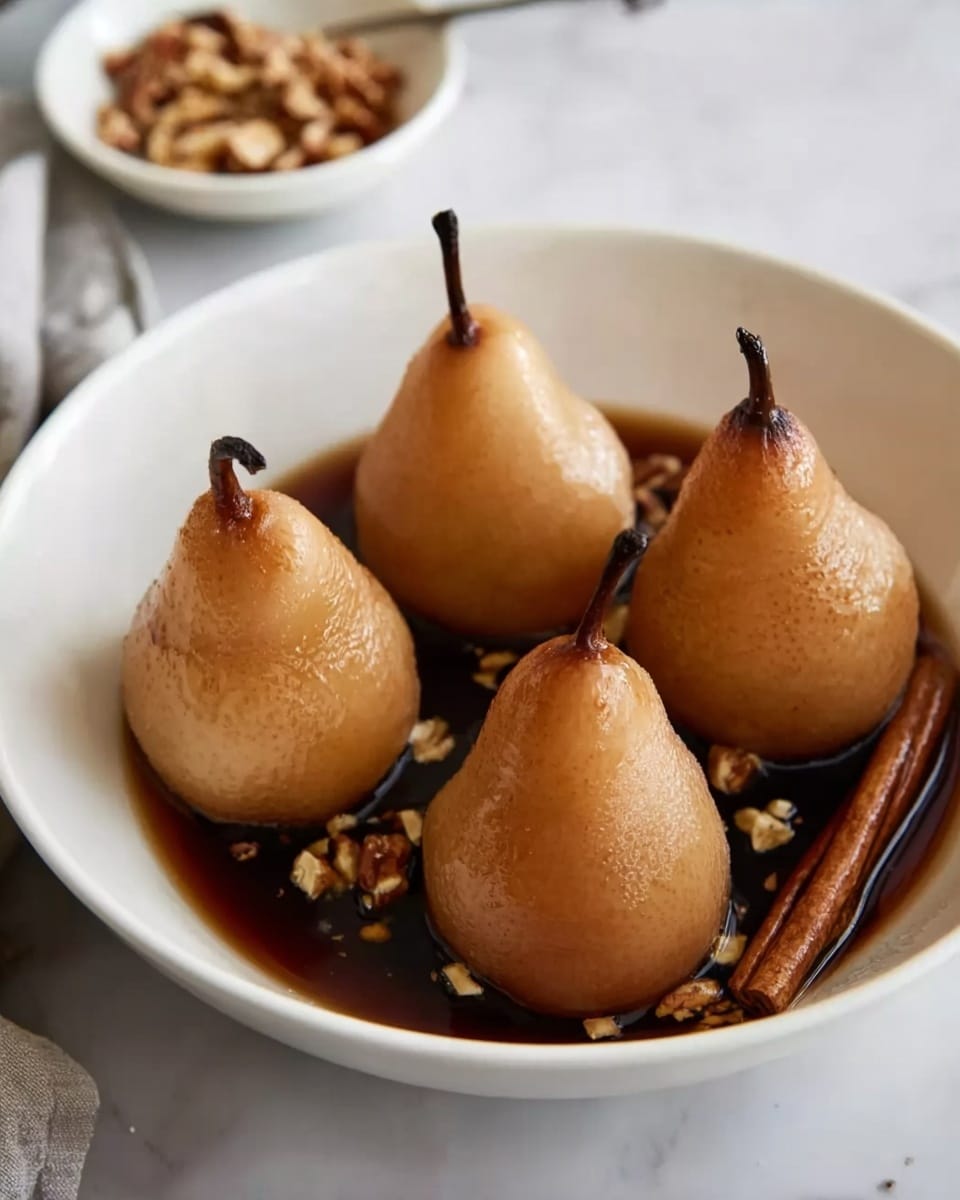 The image shows a white bowl filled with four whole pears standing upright, soaked in a dark brown liquid sauce. The pears have a smooth, golden-brown skin with a glossy texture, each with a dark stem on top. Small pieces of chopped nuts and a cinnamon stick float in the sauce around the pears, adding texture and detail to the presentation. The bowl sits on a white marbled surface with a small white dish of nuts visible in the background. Photo taken with an iphone --ar 4:5 --v 7