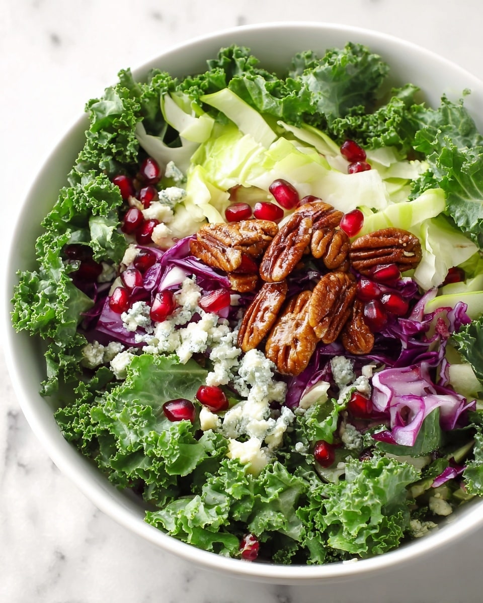 A white bowl shows a salad made of five visible layers arranged in small sections on top of leafy green kale. Starting from the left side, there is a pile of white crumbly cheese with some greenish spots, next to it is a bright red layer of shiny pomegranate seeds. To the top right of the seeds, there are small purple and white chunks of red onion. Above the onion is a cluster of brown glossy candied pecans. The kale leaves underneath are dark green with a bumpy texture. The bowl rests on a white marbled surface with a white cloth that has thin green stripes around it, and a glass measuring cup with a metal whisk is blurred in the background. Photo taken with an iphone --ar 4:5 --v 7