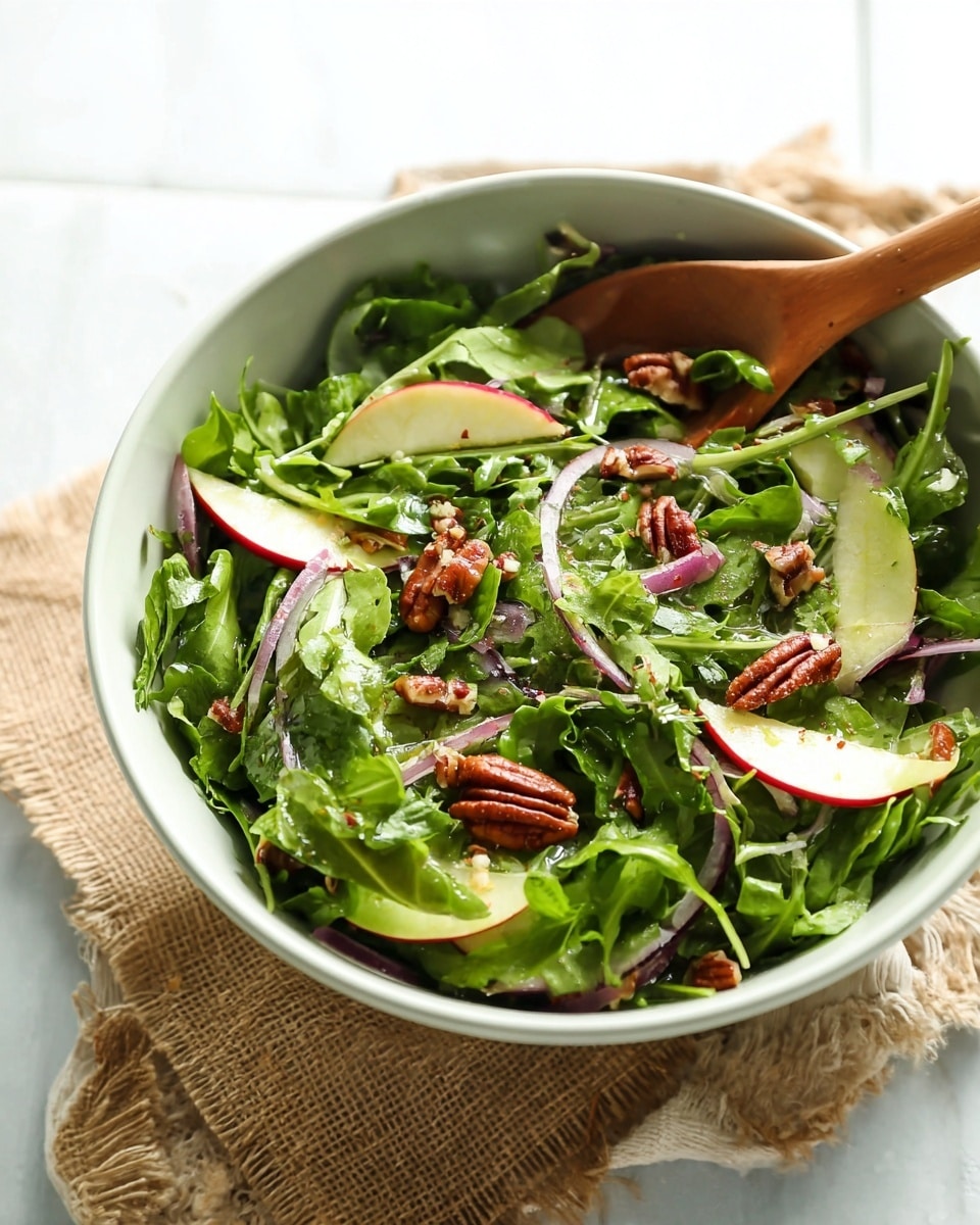 A fresh salad is shown in a white plate sitting on a white marbled surface. The salad has one main layer of green leafy arugula spread thickly over the plate. On top of the greens, there are thin slices of green apple and red onion scattered evenly, adding light green and pale purple colors with smooth and slightly crisp textures. Small clusters of dark red dried cranberries and glossy pecan halves with a rich brown color are spread over the salad, creating a mix of textures. Around the plate, two wedges of bright yellow lemon sit gently on a small piece of burlap fabric, adding a natural touch. Photo taken with an iphone --ar 4:5 --v 7