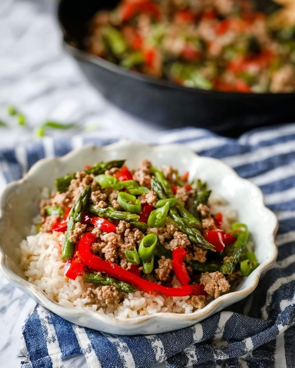 The image shows a black cast iron skillet filled with a colorful stir-fry dish placed on a wooden board with a white marbled texture surface beneath. The stir-fry is made of several layers: the base layer consists of crumbled cooked meat with a light brown color, mixed evenly throughout; on top are bright green asparagus pieces, both whole tips and chopped stalks; scattered among the asparagus are thin slices of red bell peppers adding bright red color; lastly, chopped green onions with white and green parts are sprinkled all over, giving fresh texture. The skillet is partially wrapped by a blue and white striped cloth, and a wooden spoon lies on the side. Some fresh whole asparagus stalks are placed next to the skillet. Photo taken with an iphone --ar 4:5 --v 7