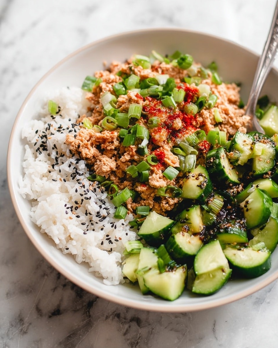 The dish is served in a white bowl on a white marbled surface, showing three main layers side by side. The bottom left section has soft white rice sprinkled with black sesame seeds. The top section contains a light brown, slightly chunky mixture with bits of red, topped with chopped green onions. The right section shows fresh, bright green cucumber cubes drizzled with a dark sauce and also sprinkled with black sesame seeds. A silver fork is placed in the rice section, lifting some rice and the brown mixture. Photo taken with an iphone --ar 4:5 --v 7