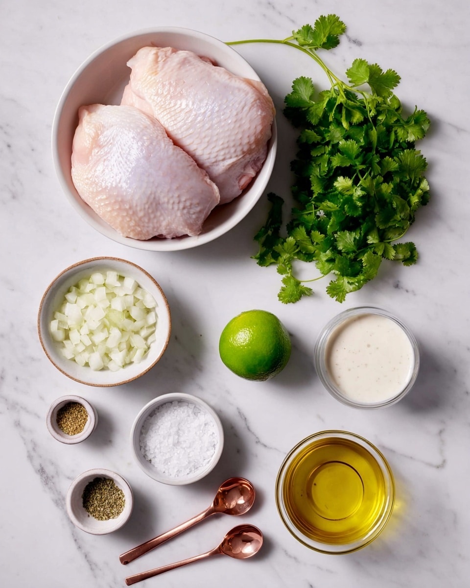 A black cast iron pan holds three cooked chicken pieces in creamy sauce that is light beige with visible herbs and small bits. Each chicken piece is golden brown with some grilled marks and topped with a bright green slice of lime and scattered fresh green cilantro leaves. The pan rests on a white marbled surface. Around the pan, there is a small white bowl with red pepper flakes, a bunch of fresh cilantro leaves, and a white bowl filled with white rice, partially visible in the corner. A white cloth is draped near the pan's handle. Photo taken with an iphone --ar 4:5 --v 7