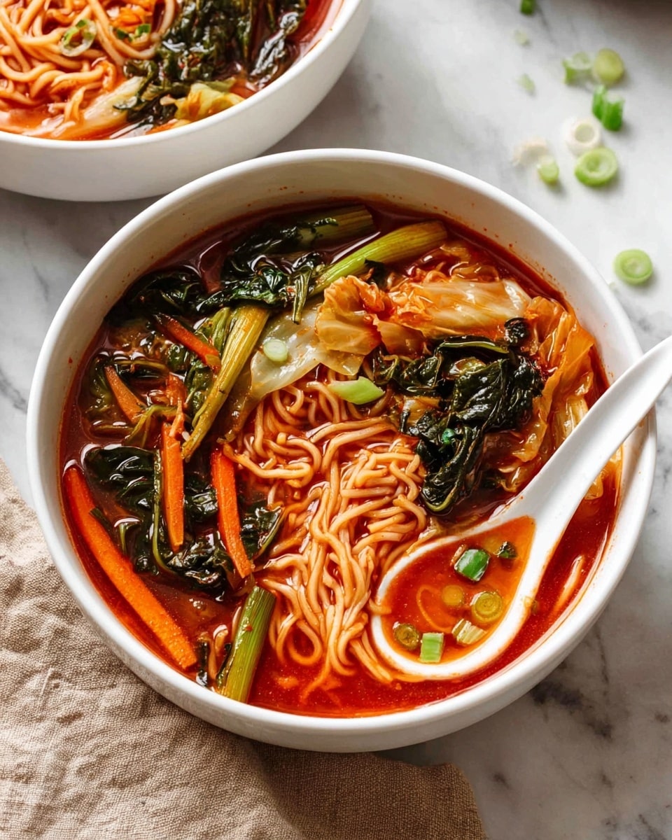 A white bowl holds a layer of light yellow noodles at the bottom, looking soft and slightly tangled. On top, there are green leafy vegetables mixed with pieces of pale orange cabbage, showing wet textures from the sauce. A ladle is pouring a bright red, slightly thick broth over the greens and noodles, the broth shimmering and showing bits of herbs floating. The background is a white marbled surface, and a woman's hand is lifting the ladle. photo taken with an iphone --ar 4:5 --v 7