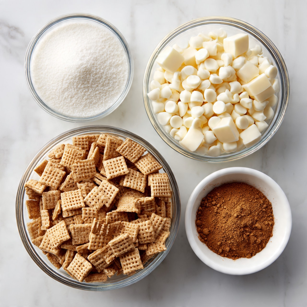 Four clear glass bowls are arranged on a white marbled surface. The largest bowl at the bottom contains many small square cereal pieces with a woven texture and light brown color. Above it on the left is a medium bowl filled with fine white powdered sugar. To the right of that is a medium bowl filled with small white chocolate chips. At the bottom right corner is a small white bowl holding a heap of ground cinnamon, which is a warm brown color. All bowls are clean and neatly placed in a balanced composition. Photo taken with an iphone --ar 4:5 --v 7