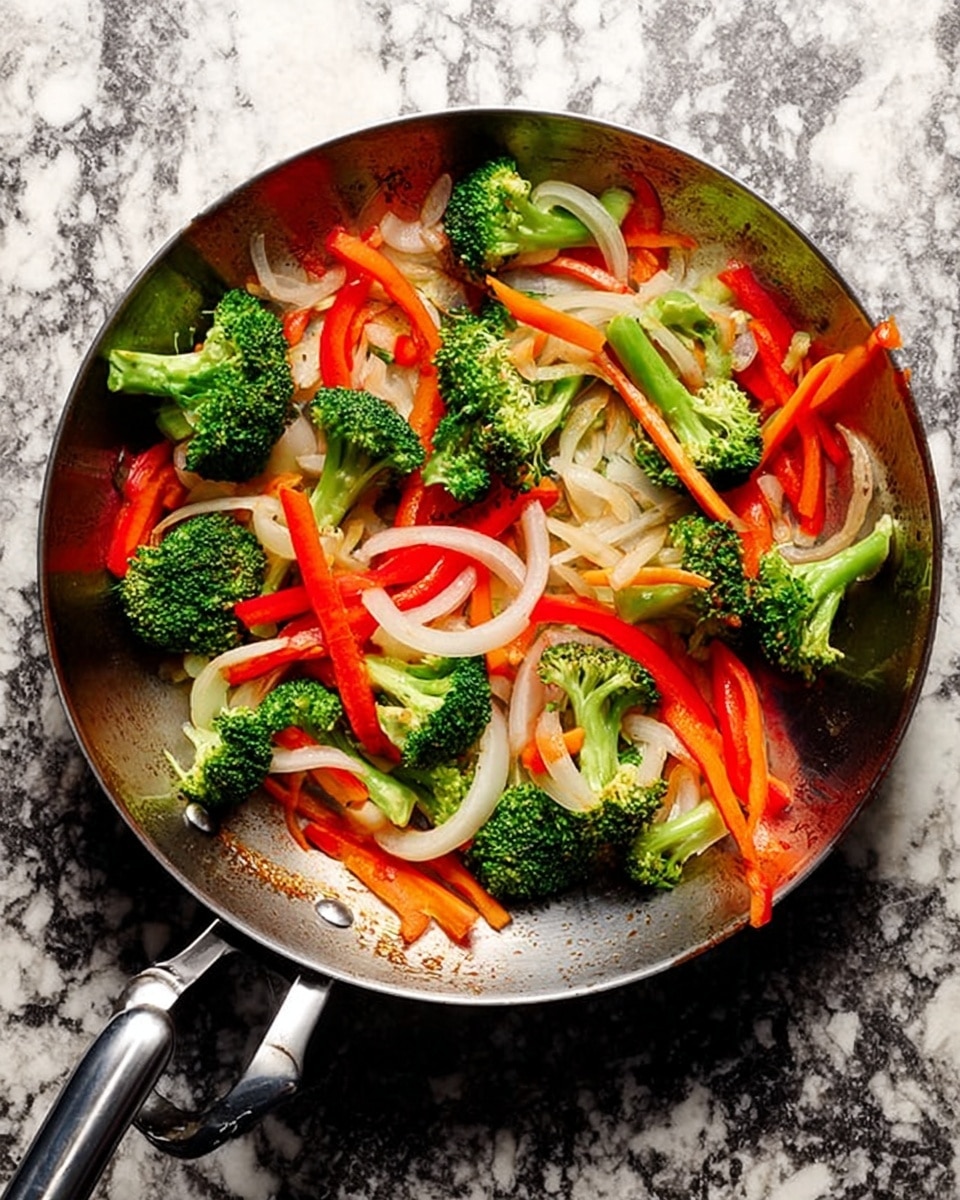 A large metal pan filled with colorful vegetables including bright green broccoli florets, thin orange carrot slices, long red bell pepper strips, and translucent white onion slices. The vegetables are spread out evenly inside the pan, showing their fresh and slightly cooked texture. The pan has a black handle and is placed on a white marbled surface, adding a clean and elegant background. photo taken with an iphone --ar 4:5 --v 7