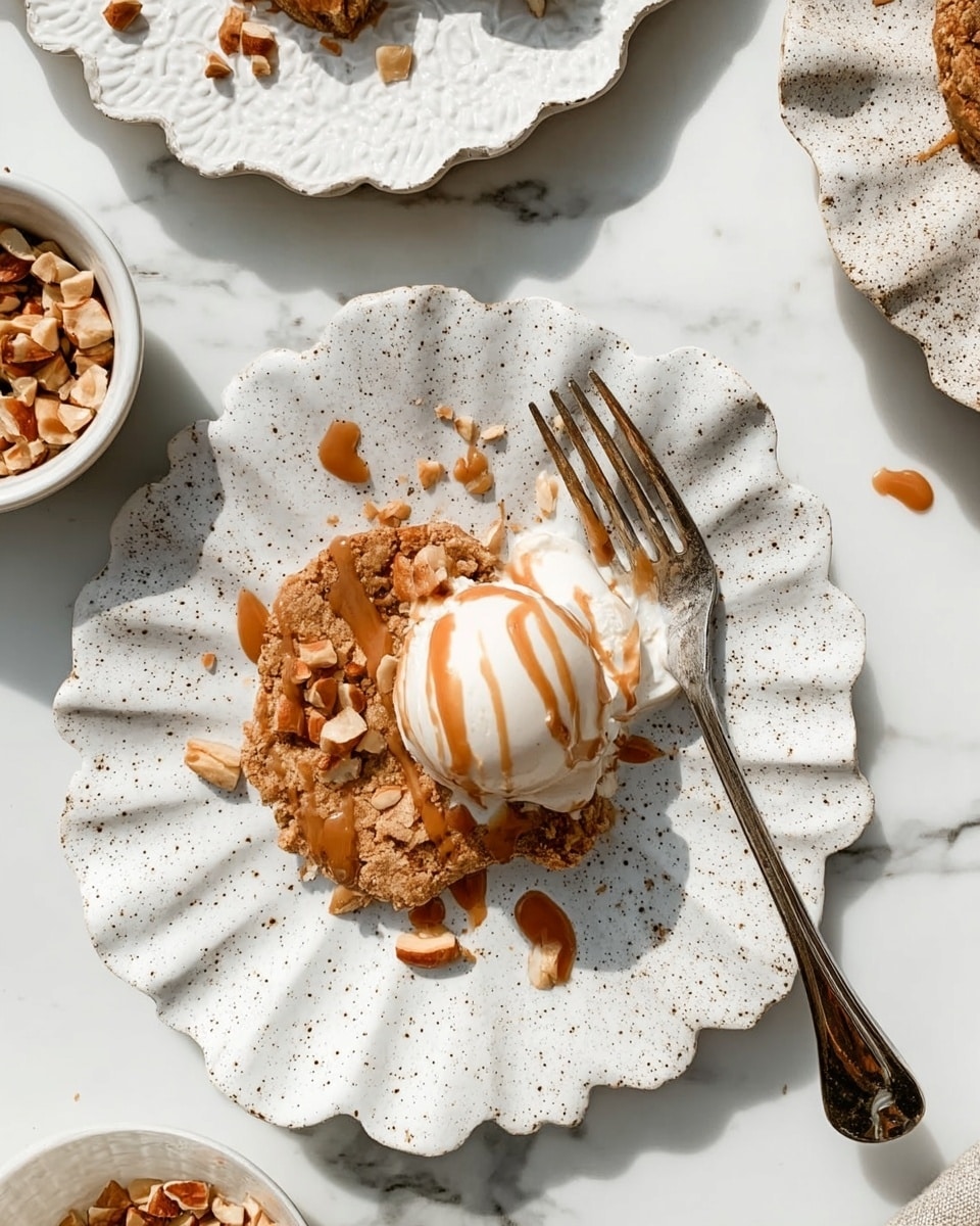 A white square baking dish filled with a crumbly, golden-brown oat topping mixed with small pieces of peanuts covering the entire surface. The oat topping looks crunchy and textured with some peanuts scattered on top. The dish is placed on a white marbled surface with a beige and white striped cloth partially under it. Around the dish, there is a white bowl with peanuts and a white plate with metal forks, adding context to the scene. Photo taken with an iphone --ar 4:5 --v 7