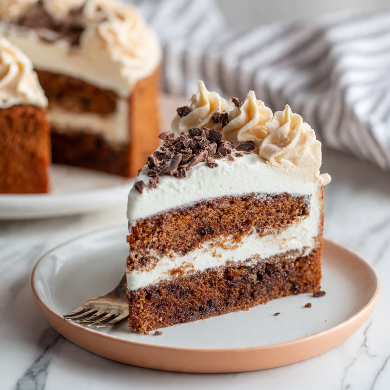 A single-layer round chocolate cake sits on a white plate with a smooth and dark brown base. Around the edge of the cake is a ring of light beige frosting shaped in soft ruffled swirls. The center of the cake is topped with thin, uneven shavings of dark chocolate that add texture. The cake is placed on a colorful striped cloth with green, red, pink, and navy lines, on a white marbled surface. In the background is a white mug with dark blue circular flower-like patterns. Photo taken with an iphone --ar 4:5 --v 7