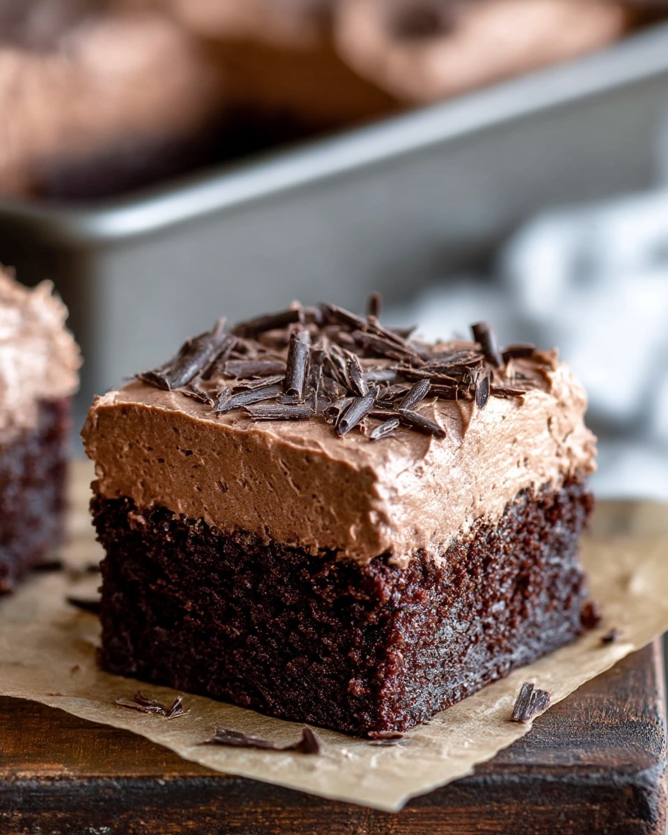 A rectangular dark chocolate cake with one thick layer of light brown chocolate frosting spread unevenly on top, showing swooping, swirled textures. The frosting is sprinkled with small chocolate shavings scattered across the surface. The cake rests on a black cooling rack placed on a white marbled surface. Next to the cake is a butter knife with some frosting on it and a small white bowl filled with dark chocolate chips. Photo taken with an iphone --ar 4:5 --v 7