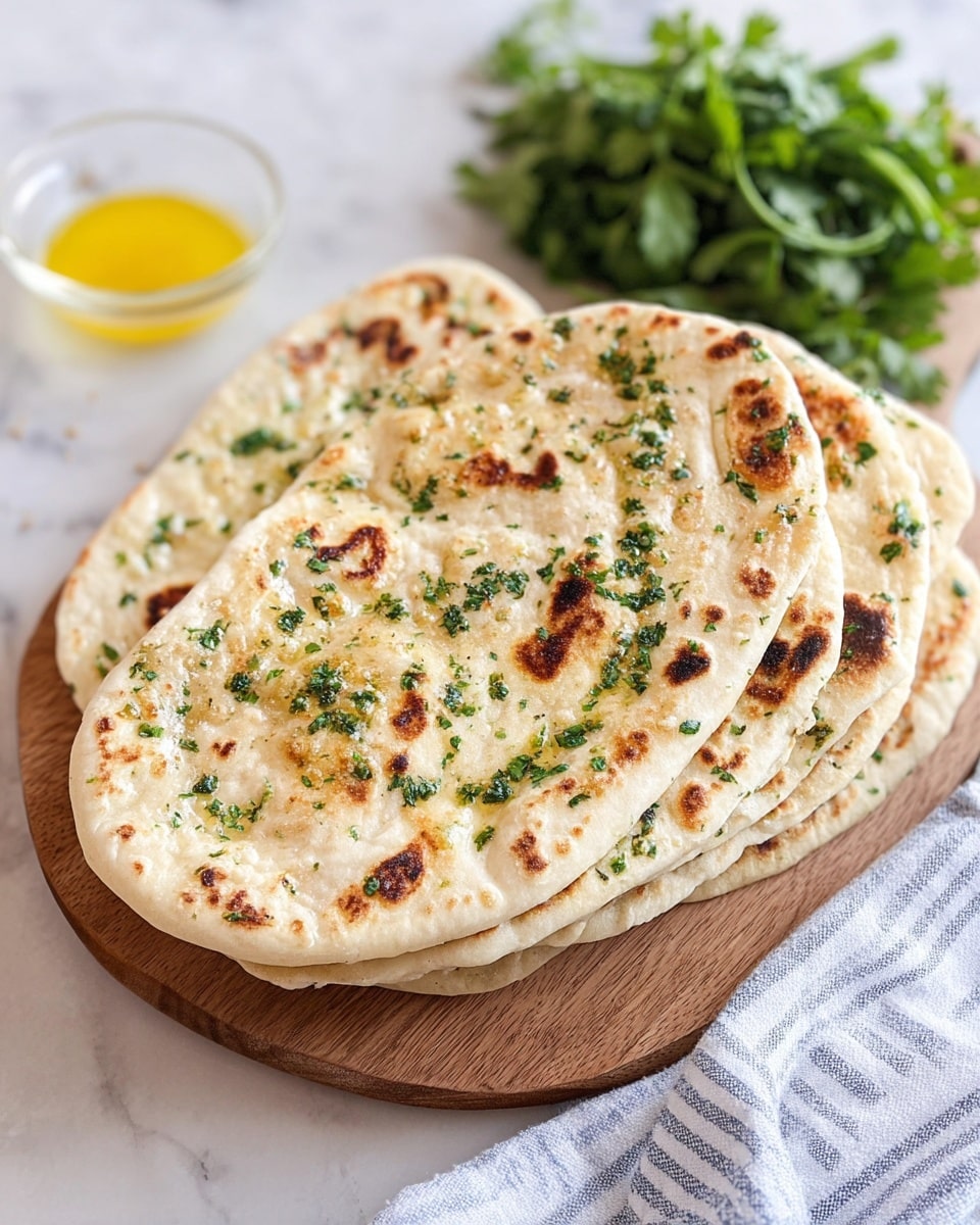 A round flatbread with slightly uneven edges is cooking in a black cast iron skillet. The flatbread has a pale creamy color with browned spots and is topped with chopped green herbs and small bits of yellow garlic or ginger spread evenly across the surface. The bread has a soft, fluffy texture with some puffed areas and light char marks. The skillet sits on a white marbled surface with a few kitchen items blurred in the background. photo taken with an iphone --ar 4:5 --v 7