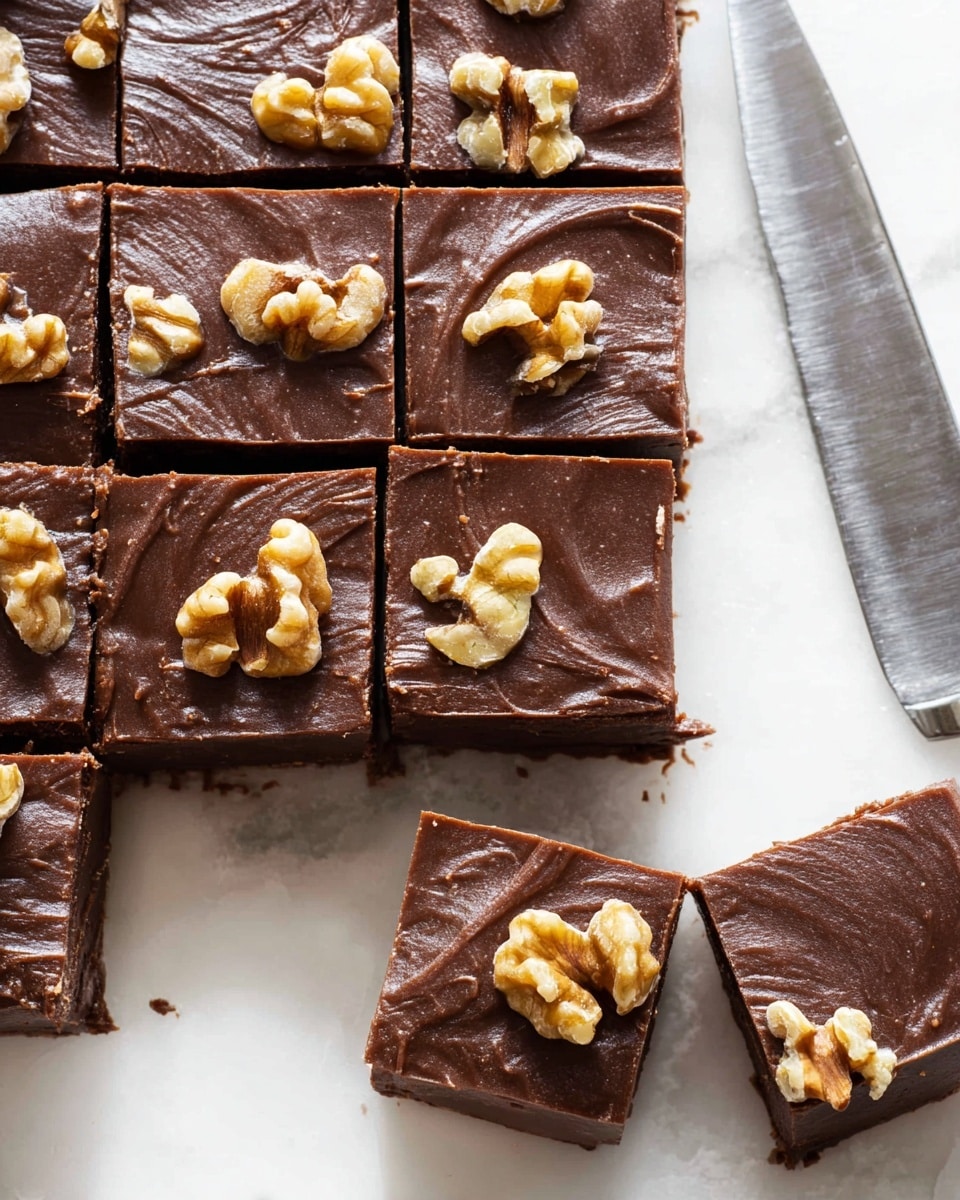 A white plate filled with many small, square chocolate brownies stacked in a pyramid shape. Each brownie piece shows a moist, dark brown texture with large chunks of light tan walnuts visible inside. The brownies have a shiny, slightly cracked top surface, and a few more brownie squares are scattered loosely around the plate on a white marbled surface. The overall look is rich and nutty, with the contrast between the dark chocolate and light walnut pieces clearly visible photo taken with an iphone --ar 4:5 --v 7