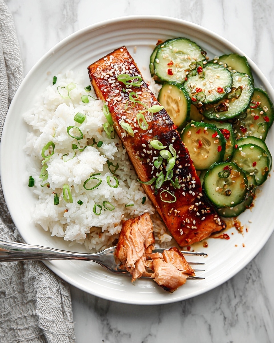 A white plate holds a meal with three main layers. On the bottom left is a soft, fluffy layer of white rice sprinkled with chopped green onions. On top of the rice, near the middle, lies a thick, grilled piece of salmon with a shiny, caramelized brown crust, topped with sesame seeds and sliced green onions. To the right of the salmon, there is a portion of sliced cucumber salad, showing bright green cucumber pieces mixed with small sesame seeds and red chili flakes. A fork rests on the rice with small salmon pieces on it, and the plate sits on a white marbled surface. photo taken with an iphone --ar 4:5 --v 7