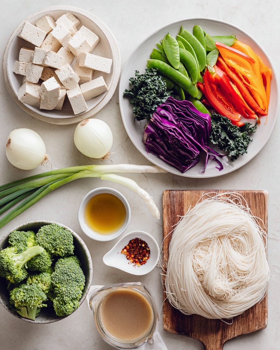 This image shows a flat lay of fresh ingredients on a white marbled surface. In the top left, there is a white plate filled with pale pink cubes of tofu. Below it, a white plate holds colorful fresh vegetables: deep purple cabbage, bright green snap peas, vibrant orange bell pepper strips, dark green kale, and a few green onions extending from the plate to the center. To the right, two white onions sit next to a white spoon heaped with red chili flakes and a white bowl filled with golden oil. Below these is a wooden board covered with thin pale rice noodles. In the bottom left corner, a white bowl is filled with bright green broccoli florets. Lastly, a clear glass cup holds a beige sauce with a white ceramic spoon inside. photo taken with an iphone --ar 4:5 --v 7