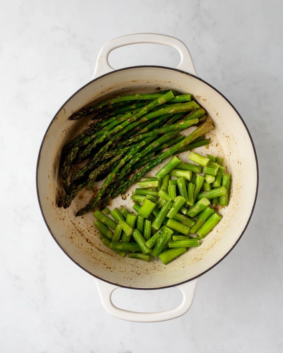 A white bowl holds creamy risotto as the base layer, showing soft, pale grains mixed with bright green peas scattered throughout. On top, a few shiny, grilled asparagus stalks lay across the risotto, each one vibrant green with slight char marks. At the back edge of the bowl, a yellow lemon wedge adds a pop of color. The bowl sits on a white marbled surface, and a fork is placed inside the bowl on the left side. The whole scene is softly lit, highlighting the textures and colors of the dish photo taken with an iphone --ar 4:5 --v 7