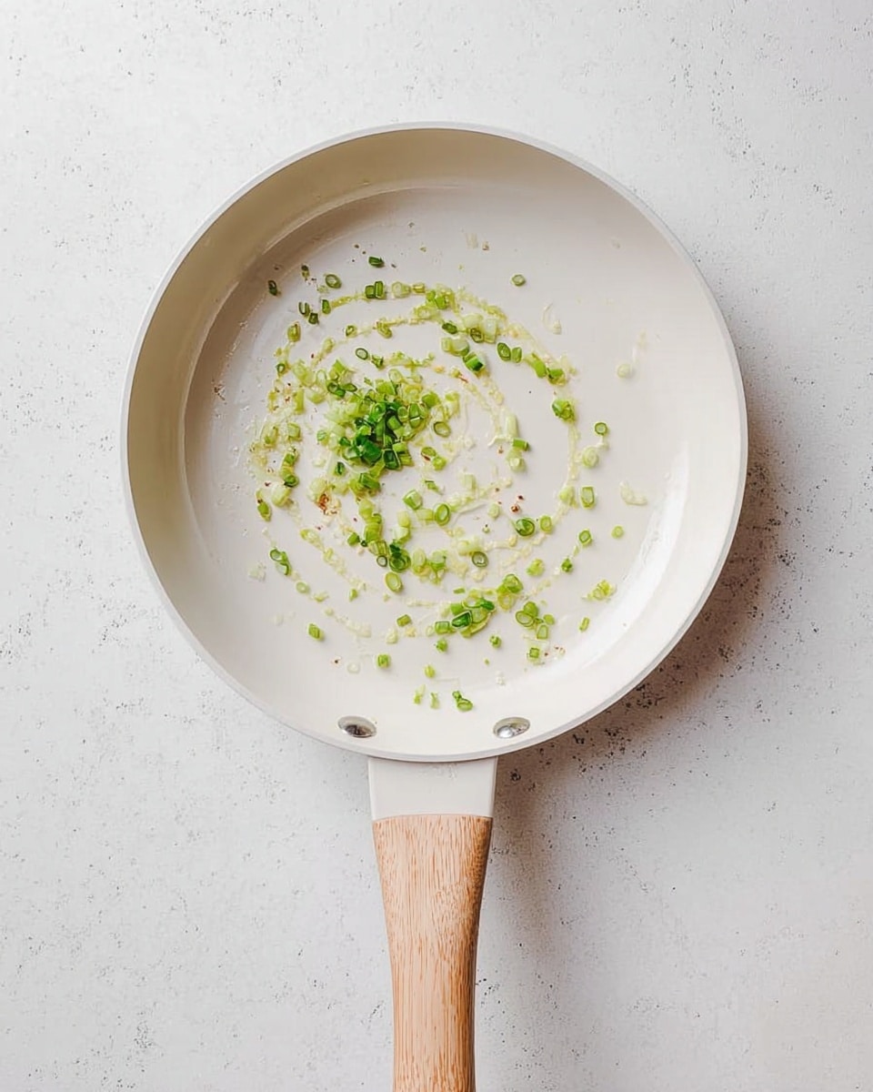 A white bowl filled with creamy mashed potatoes that have small green onion pieces mixed in, topped with a square of melting butter in the center and more chopped green onions sprinkled on top. The bowl sits on a white cloth with green leaf patterns and a wooden spoon rests on the right side of the cloth. There are two whole potatoes and two glasses filled with iced drink on the white marbled surface around the bowl, along with a head of garlic and a small white bowl containing more chopped green onions. Photo taken with an iphone --ar 4:5 --v 7