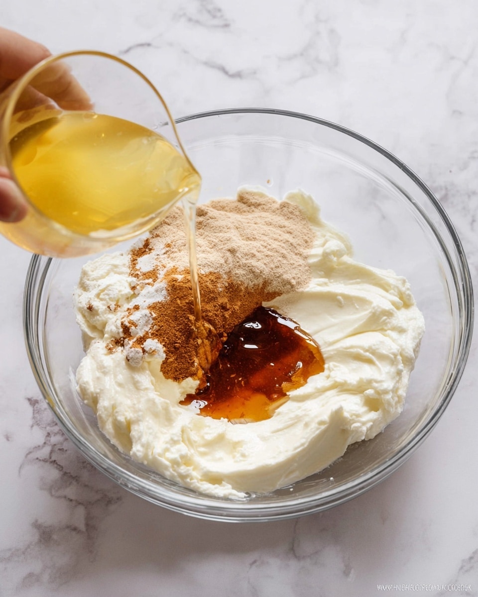 A clear glass bowl on a white marbled surface holds different ingredients before mixing. The bottom layer is thick and white, creamy texture. On top, there is a pile of light brown powder on one side and a dark amber liquid spread nearby. A yellow liquid is being poured from a glass into the bowl from the left side, held by a woman's hand. The ingredients have distinct colors and textures, sitting separately in the bowl. Photo taken with an iphone --ar 4:5 --v 7