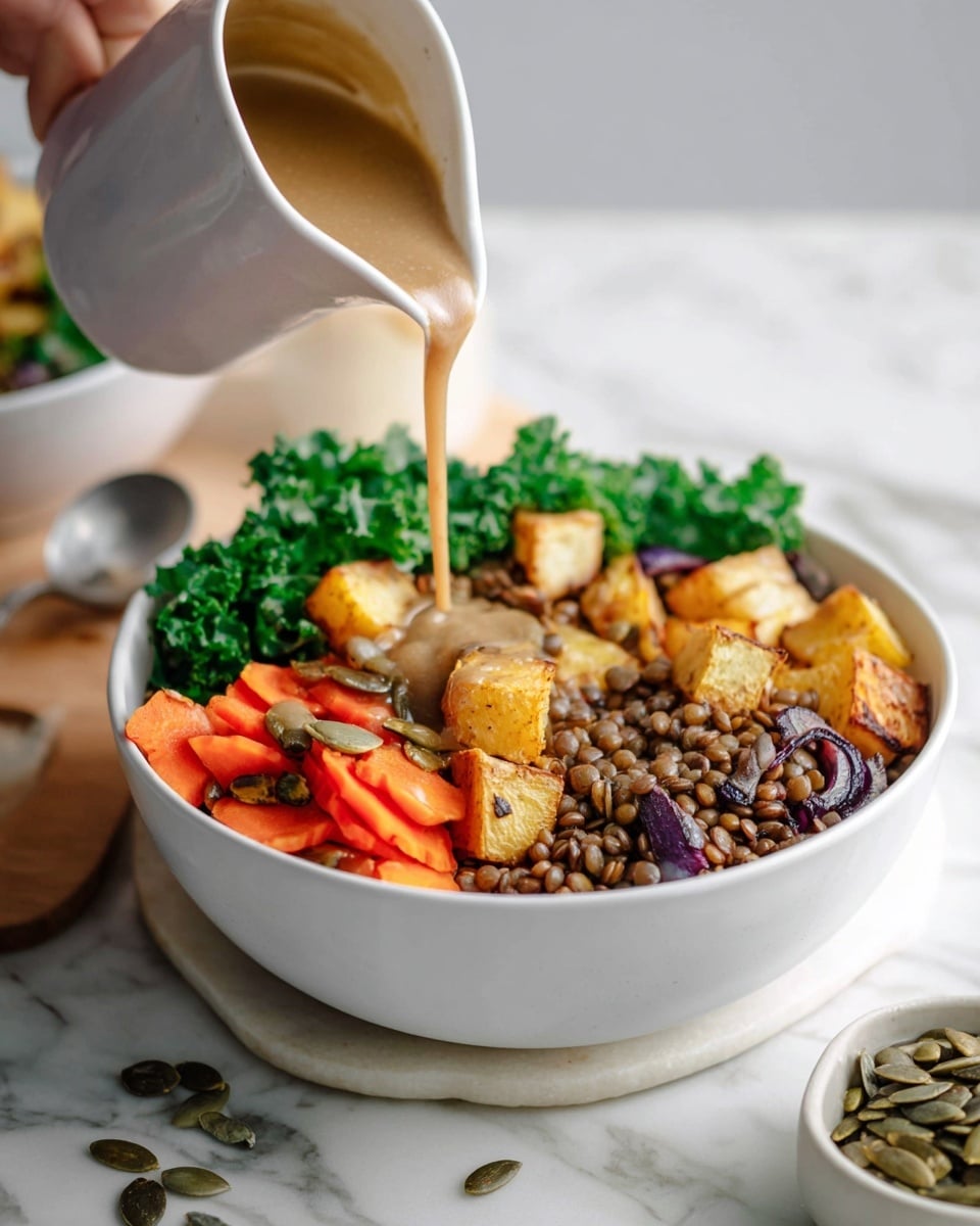 The dish shows a white bowl with three main layers. The bottom layer is fresh, green kale leaves that look crisp. On top of the kale, there are chopped roasted orange carrots and red onions, giving a mix of soft textures and bright colors. Next to the veggies, there are small roasted potato pieces with a golden-brown color. Light brown lentils fill the last part of the bowl, creating a grainy texture contrast. Everything is drizzled with a creamy sauce that is a soft tan color, and some pumpkin seeds sprinkle on top for extra detail. The background has a white marbled texture, and behind the main bowl, a second bowl and a spoon are slightly blurred. photo taken with an iphone --ar 4:5 --v 7