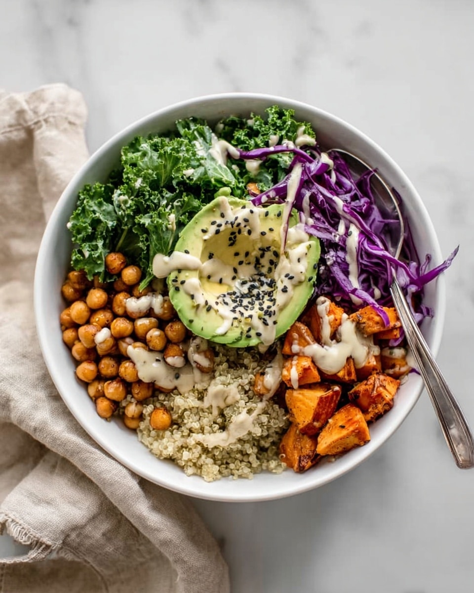 A white bowl filled with five main layers: at the top right, curly green kale leaves; next to it on the top left, small brown chickpeas; on the left middle, thin shredded purple cabbage; below the cabbage is a beige grain base, likely quinoa; at the bottom right, orange roasted chunks, possibly sweet potato. At the center is a halved avocado with black sesame seeds sprinkled on top, drizzled with a creamy light sauce that also covers the other ingredients lightly. A silver spoon is placed inside the bowl on the kale side. The bowl sits on a white marbled texture surface with a beige cloth loosely folded nearby. Photo taken with an iphone --ar 4:5 --v 7