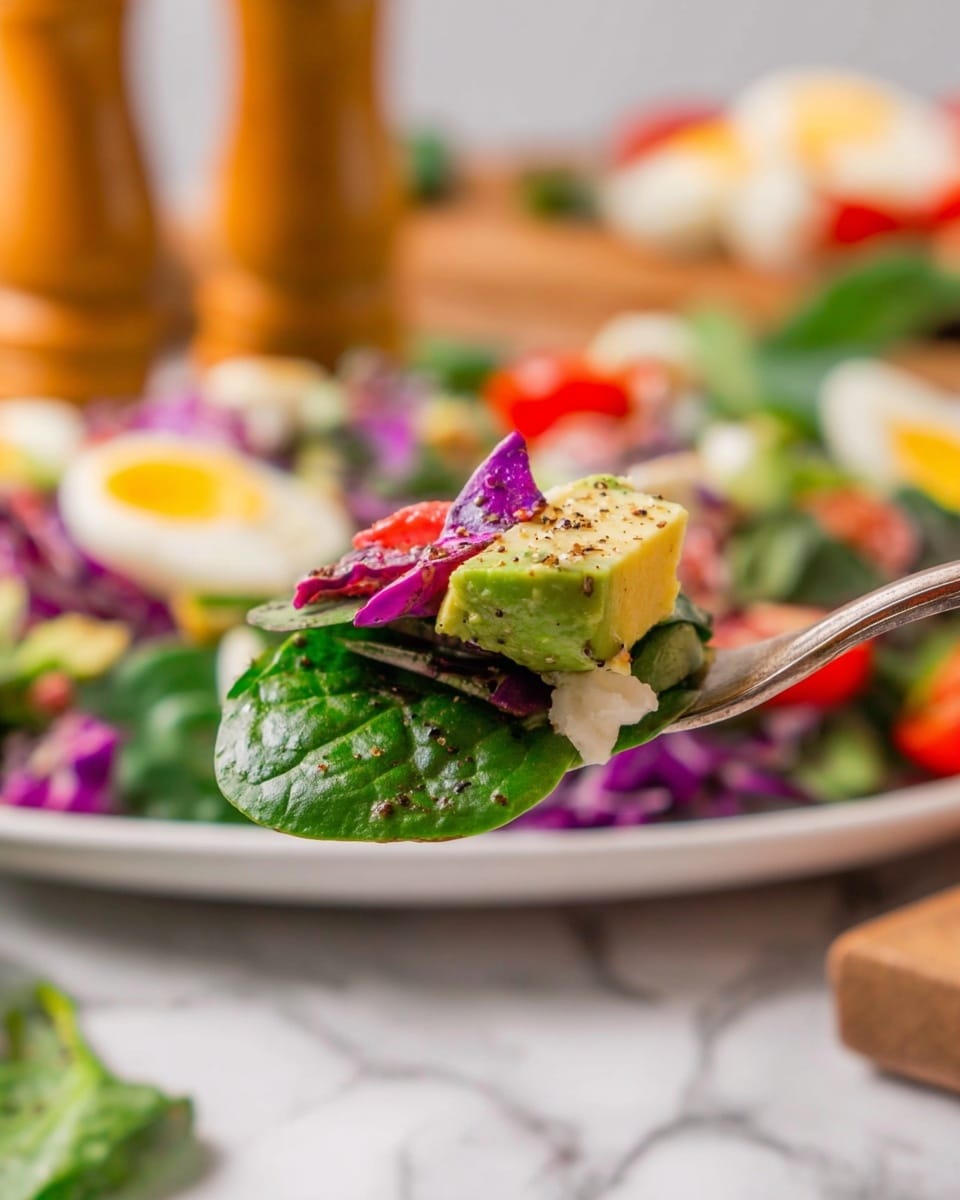 A wooden tray with six colorful layers of food is shown from above on a white marbled surface. From top to bottom, the first layer is fresh, dark green spinach leaves. The second layer is thinly sliced rings of red onion in light purple and white. The third layer features slices of hard-boiled eggs with bright white and yellow colors. The fourth layer shows shredded purple cabbage adding a bold, rich color. The fifth layer is small pieces of cooked bacon in reddish brown. The bottom, sixth layer shows diced ripe avocado in green on top of more spinach leaves. At the very bottom, bright red cherry peppers line the tray. On the right side is a small glass container with light yellow dressing and a spoon. Photo taken with an iphone --ar 4:5 --v 7