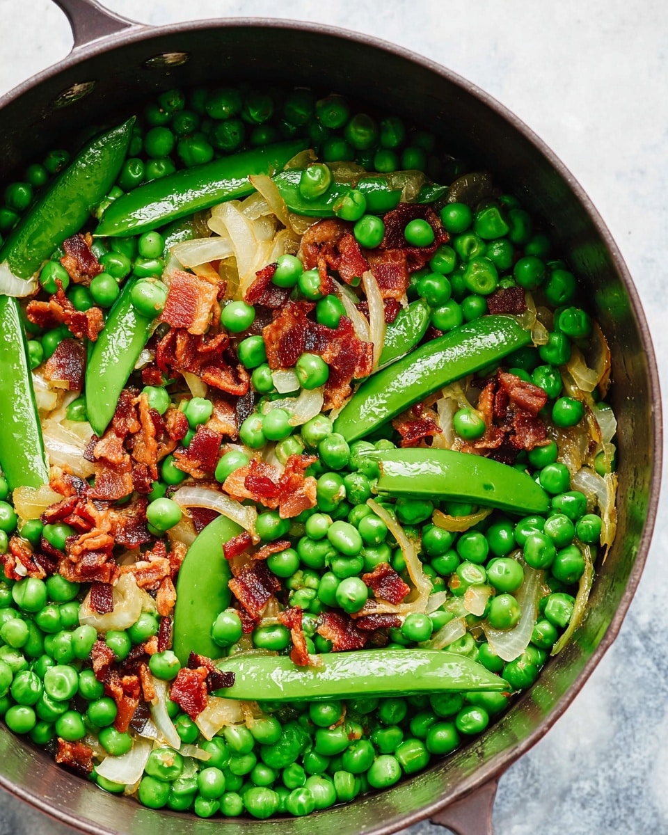 A close-up view of a fresh pea salad served on a white plate with a textured pattern. The dish has multiple layers starting with bright green peas and snap peas, mixed with light green fresh mint leaves spread across the dish. Scattered on top are small pieces of crispy light brown and slightly orange bacon bits, adding a crunchy texture. Thin slices of pale onion rings add softness among the greens, and a few drops of olive oil glisten over the salad. A silver spoon rests on the right side of the plate, partially immersed in the salad. The whole setting is on a white marbled textured surface. Photo taken with an iphone --ar 4:5 --v 7