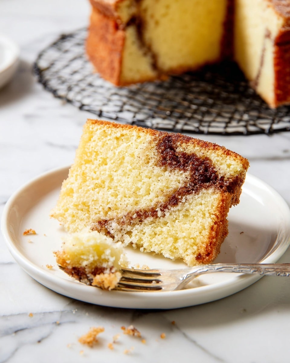 A loaf of cinnamon swirl cake is shown on a round wire cooling rack with a white marbled surface underneath. The cake has a golden-brown crumb topping with a glaze drizzled over it, arranged in small rectangular sections on top. Next to it, there are two white plates each holding a single slice of the cake. The slice reveals a soft yellow cake with a thick dark brown cinnamon swirl inside. Two cups of black coffee in white mugs are also visible in the scene, along with two dark grey forks resting on the white marbled surface. Photo taken with an iphone --ar 4:5 --v 7