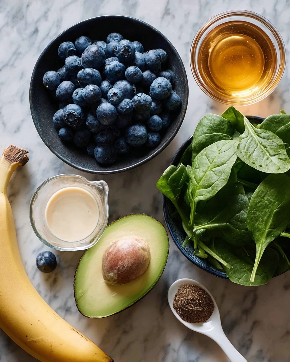 A bunch of fresh blueberries fills a small black bowl with two blueberries outside it, placed on a white marbled surface. To the right of the bowl, there is a small round glass container filled with golden honey. Below the honey is a dark bowl full of fresh green spinach leaves. At the center is a half avocado showing a green inside with a large brown pit. Below the avocado lies a glass measuring cup filled with creamy light beige liquid. On the left bottom corner there is a ripe yellow banana. Next to the measuring cup, a white spoon holds a dark brown powdery spice. Photo taken with an iphone --ar 4:5 --v 7