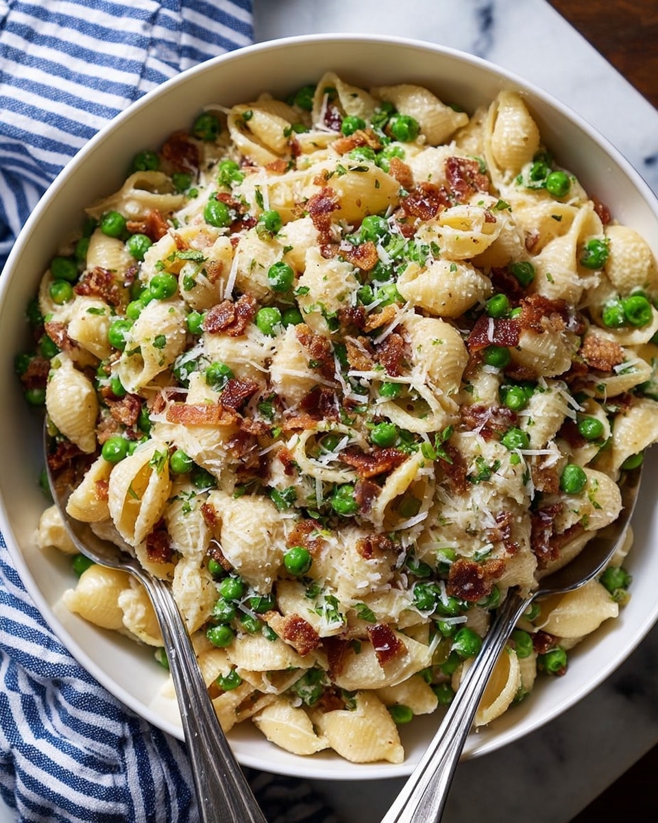 This image shows a close-up of a creamy pasta dish with shell-shaped pasta mixed with light green peas, small bits of crispy reddish-brown bacon, and thin white shredded cheese scattered on top. The pasta shells are covered in a smooth, creamy white sauce with a slightly glossy texture. The colors mostly are light yellow from the pasta, fresh green from the peas, and the dark red of bacon bits, making a colorful contrast. The ingredients are tightly packed together, creating a rich, creamy, and textured look. photo taken with an iphone --ar 4:5 --v 7