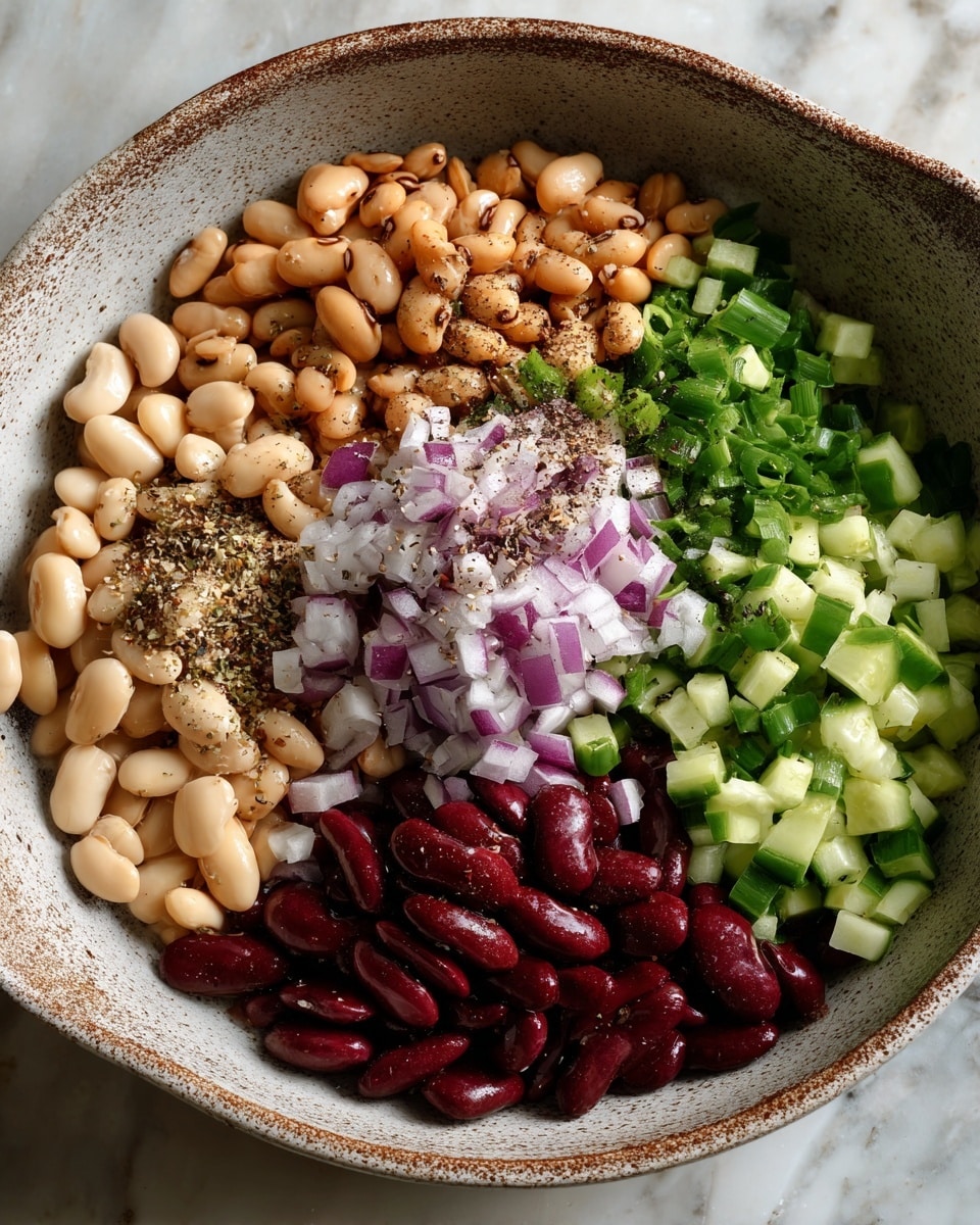A round, speckled white bowl holds six distinct layers of ingredients arranged like a colorful pie chart. At the top right are tan beans with dark spots, next to bright green diced cucumber pieces on the far right. Centered, there is a mound of finely chopped purple and white onions sprinkled with black pepper. Below the onions, there are light brown beans, and to the bottom left, deep red kidney beans. The last section, at the top left, contains pale beige beans, also dusted with black pepper. The bowl sits on a white marbled surface. Photo taken with an iphone --ar 4:5 --v 7