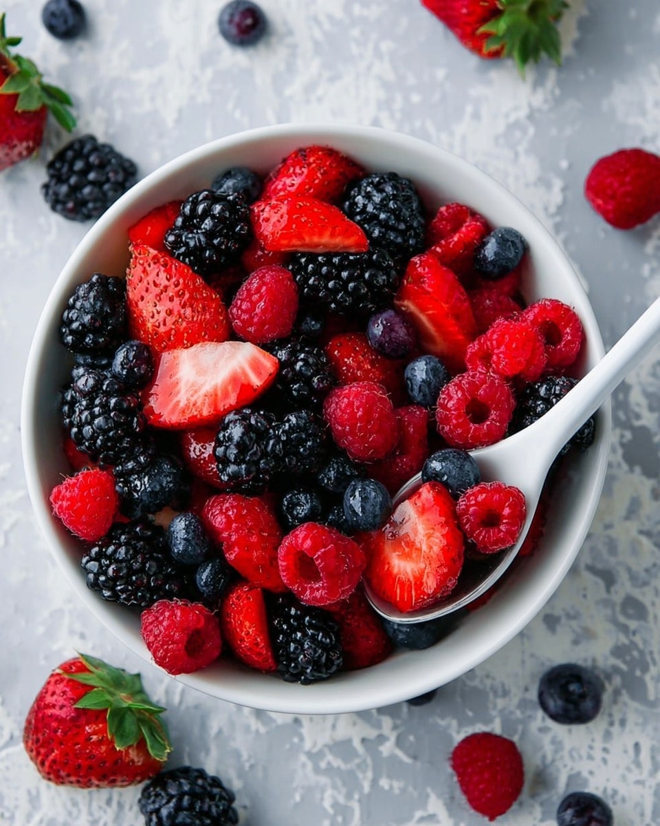 A white bowl full of fresh mixed berries, with three main layers: the bottom layer mostly dark blackberries with shiny, bumpy texture, the middle layer bright red raspberries with soft texture and hollow centers, and the top layer large red strawberries, some halved to show their juicy, bright red insides with seeds dotted outside. Small blueberries are scattered throughout the bowl, adding deep blue color, and the background is a white marbled surface with some green leaves blurred in the back. photo taken with an iphone --ar 4:5 --v 7