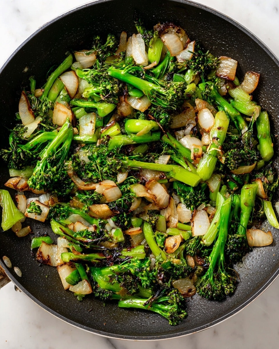 A close-up top view of a black frying pan filled with cooked chopped broccolini and onions, showing a mix of green and light brown pieces with some charred edges. The broccolini bits have dark and light green colors and a slightly rough texture, while the onion pieces are light beige to tan with a soft, translucent look and some caramelized edges. The pan rests on a white marbled surface. photo taken with an iphone --ar 4:5 --v 7