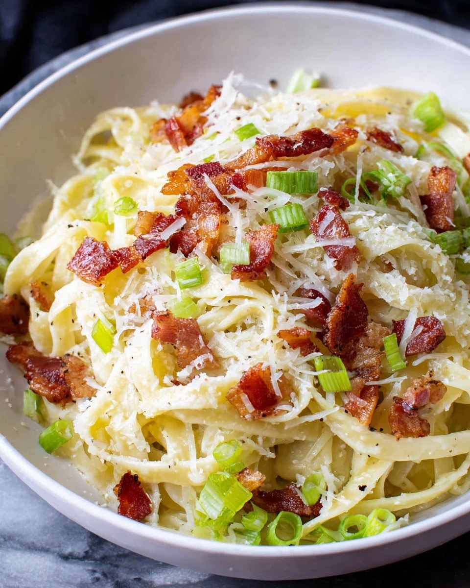 A close-up of a dish in a white bowl filled with thin, pale yellow and white wide noodles layered at the bottom, topped with small crispy browned bacon pieces scattered evenly, light green sliced scallion strips sprinkled on top, and finely grated white cheese covering part of the noodles. The bowl sits on a white marbled surface. photo taken with an iphone --ar 4:5 --v 7
