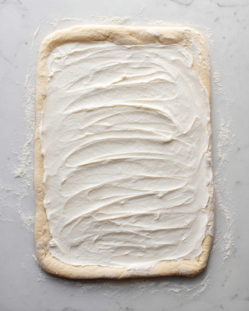 Two slices of purple and white swirled bread with a soft texture are placed on white plates, showing layers of purple berry filling marbled through the light, fluffy bread. One slice is on the bottom plate, and the other slice is on the top right plate. Beside them, on the left side, part of a loaf with the same purple swirl is resting on crumpled parchment paper over a woven round mat. A white soft cloth drapes around the plates, all placed on a white marbled surface. photo taken with an iphone --ar 4:5 --v 7