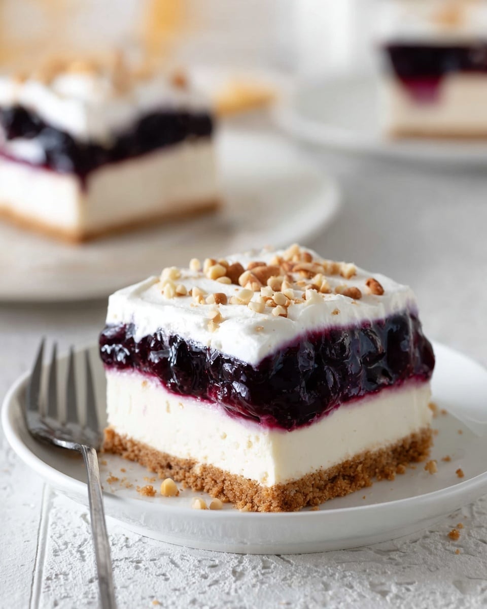 A square dessert with four clear layers sits on a white plate over a white marbled surface. The bottom layer is light brown, crumbly, and looks like a crust. Above that is a thick creamy white layer, smooth and firm. The third layer is a glossy deep purple jelly-like fruit topping with visible small fruit pieces in it. On top is a thick, fluffy white cream layer sprinkled with small pieces of light brown nuts scattered evenly. In the background, there is another white plate with the same dessert slightly out of focus and a silver fork on the left side. The whole scene has soft, natural lighting. photo taken with an iphone --ar 4:5 --v 7