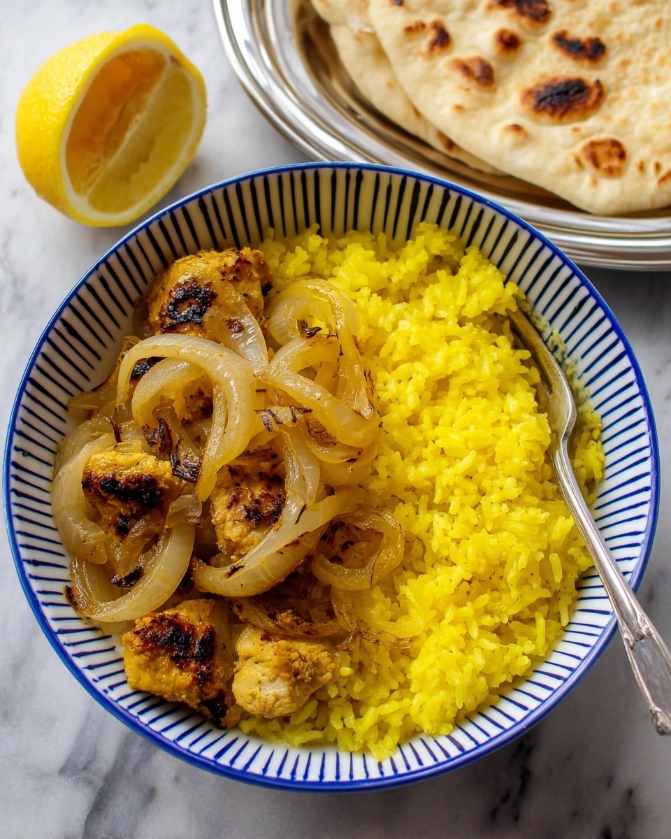 A close-up view of a black pan filled with several pieces of cooked chicken coated in a thick yellow curry sauce, mixed with translucent cooked onion slices spread evenly throughout. In the center, there is a half lemon placed on top of the chicken and sauce, showing the inner segments clearly. The chicken has some charred, dark brown spots giving it a slightly toasted look. The pan sits on a white marbled surface. photo taken with an iphone --ar 4:5 --v 7